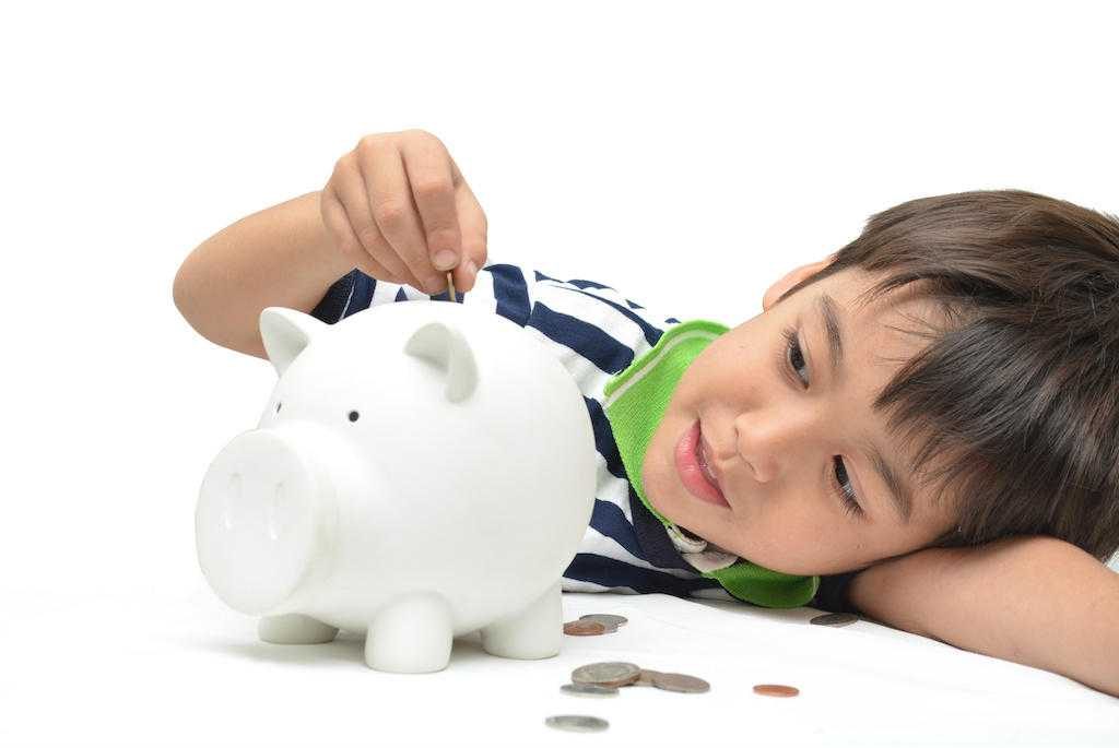 Little boy saving money in piggy bank